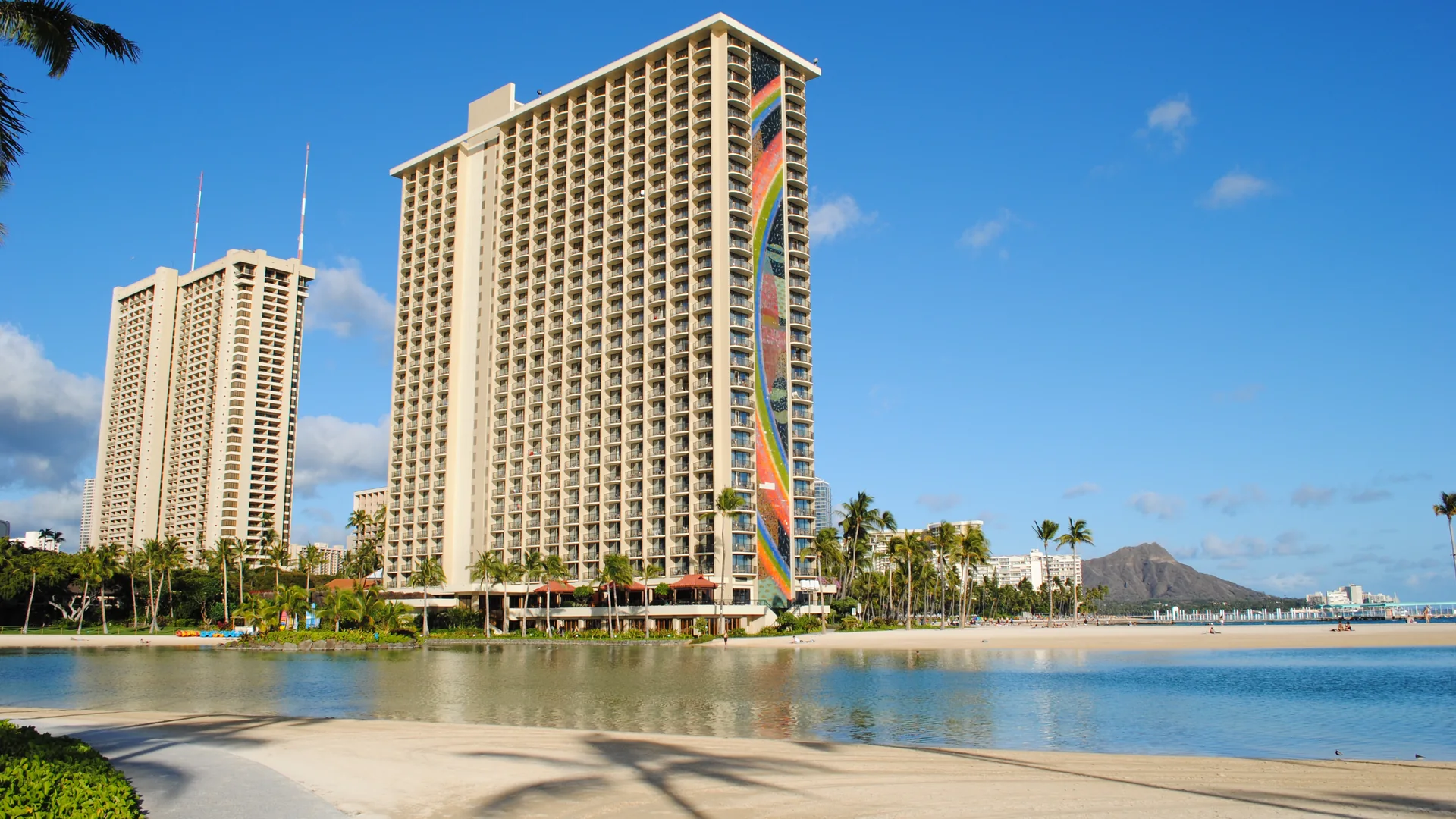 Rainbow Tower v Hilton Hawaiian Village vedle své laguny, s palmami, pláží a Diamond Head v dohledu